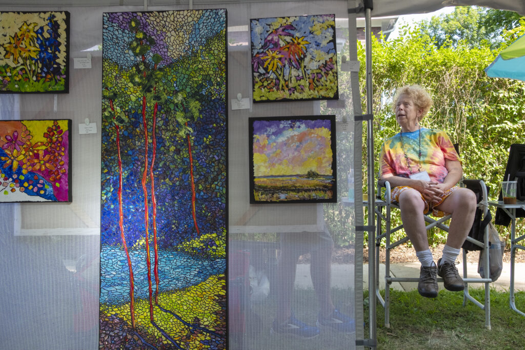 Painter Carrie Jacobson sits next to her booth at the 2018 festival. (Photograph by Will Yurman)