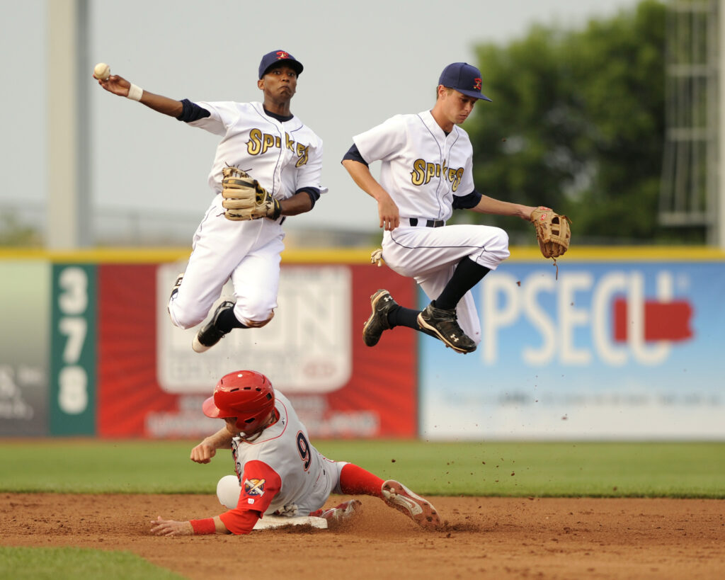 Infielders for the State College Spikes jump over a sliding player trying to complete a double play. (Photograph by